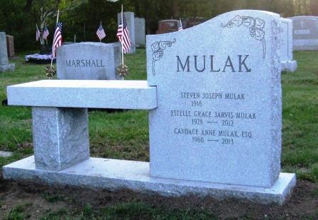 A headstone with a simple looking attached bench