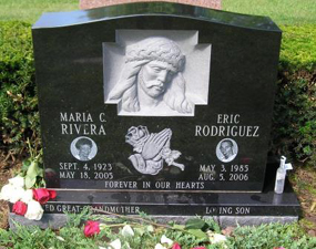 Religious art and small photos on an engraved black headstone
