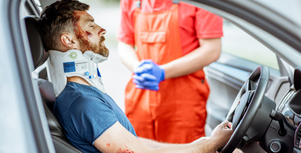 Un hombre con lesiones recibiendo atención médica en su auto después de un accidente