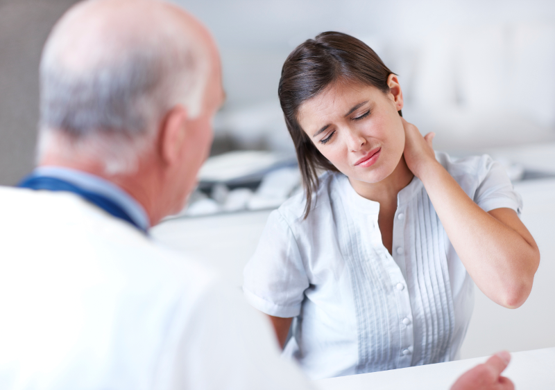 Una mujer mostrando molestias en el cuello en el quiropráctico