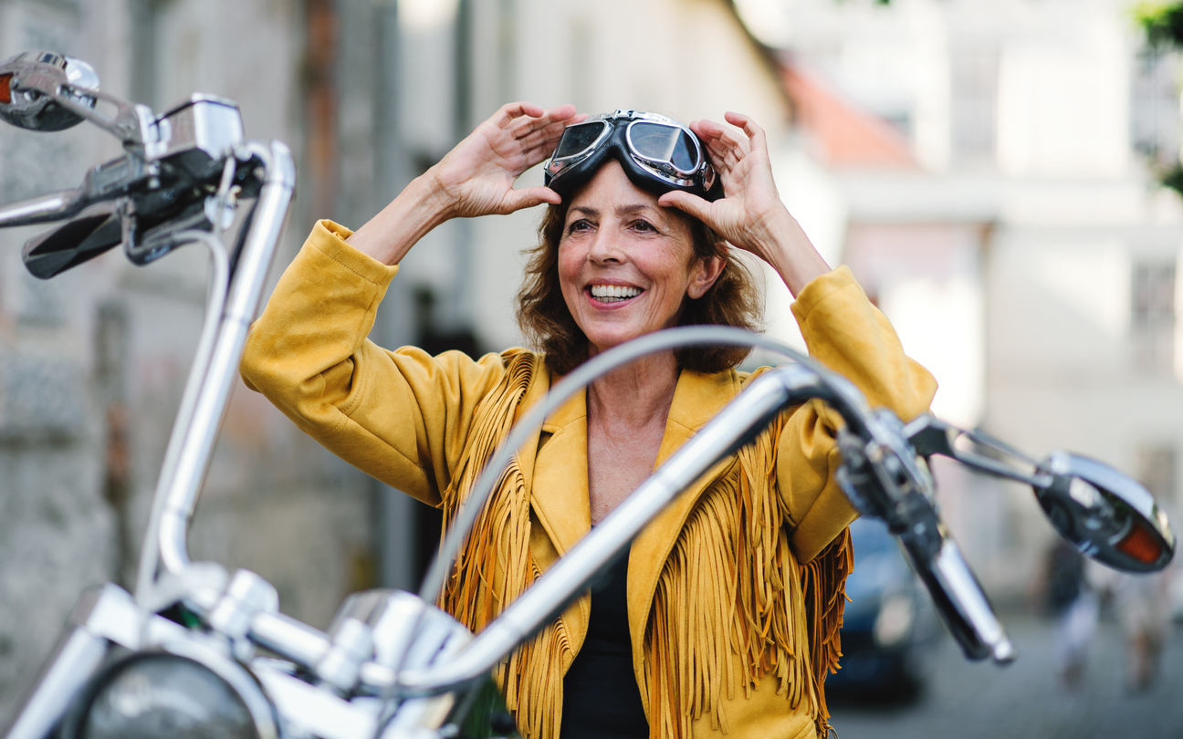 Una señora subida a una moto poniéndose unas gafas