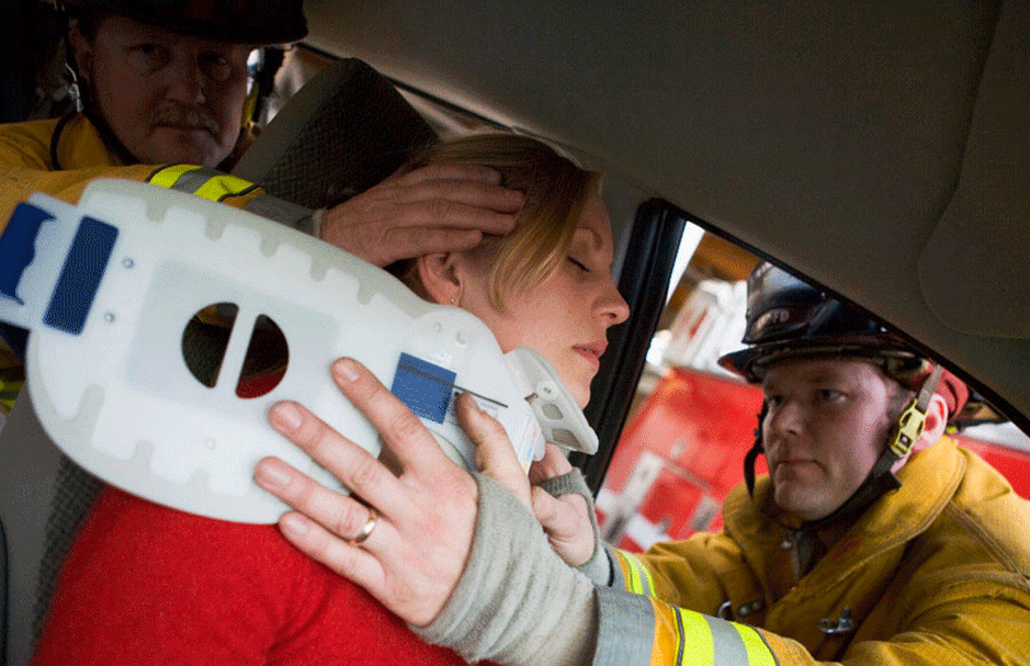 Una mujer lesionada en un accidente de auto. Los bomberos la están atendiendo de sus leisones