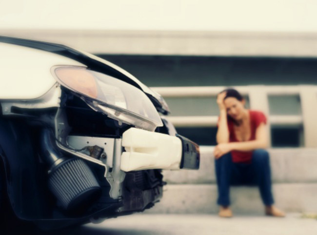 Una mujer lesionada sentada en la acera después de sufrir un accidente de auto