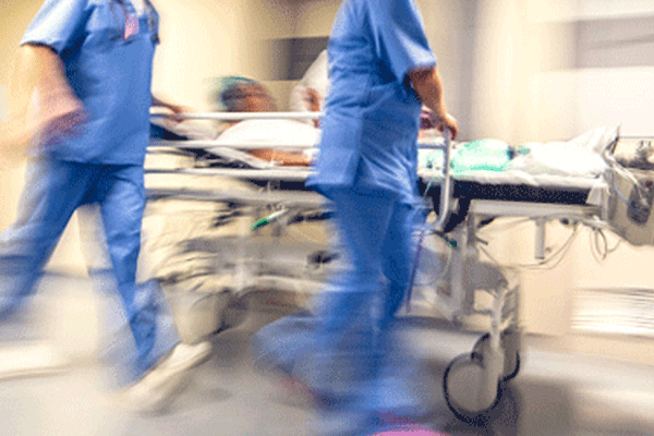 Dos enfermeros en el hospital empujando una camilla con una persona lesionada
