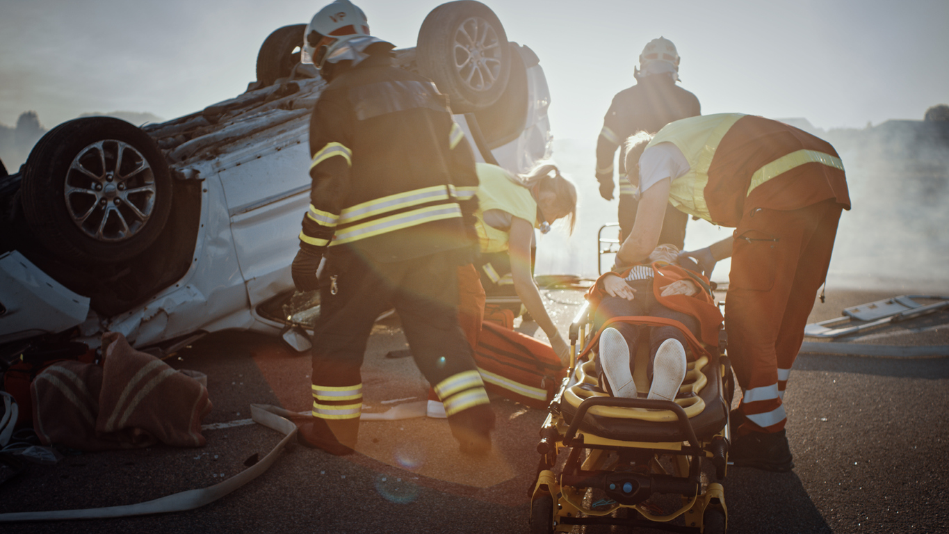 Una persona lesionada en un accidente en una camilla siendo atendida por los servicios de emergencia
