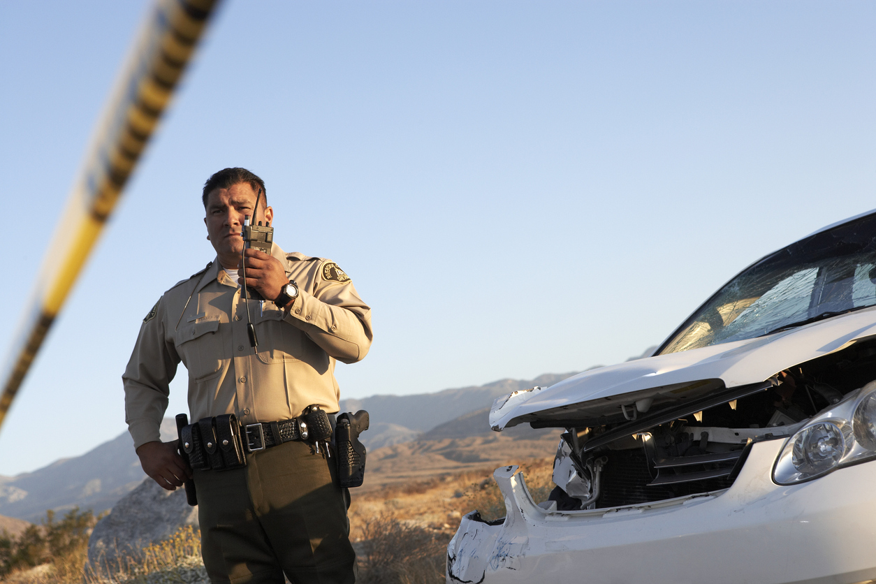 A police officer evaluation an auto accident to prepare a police report