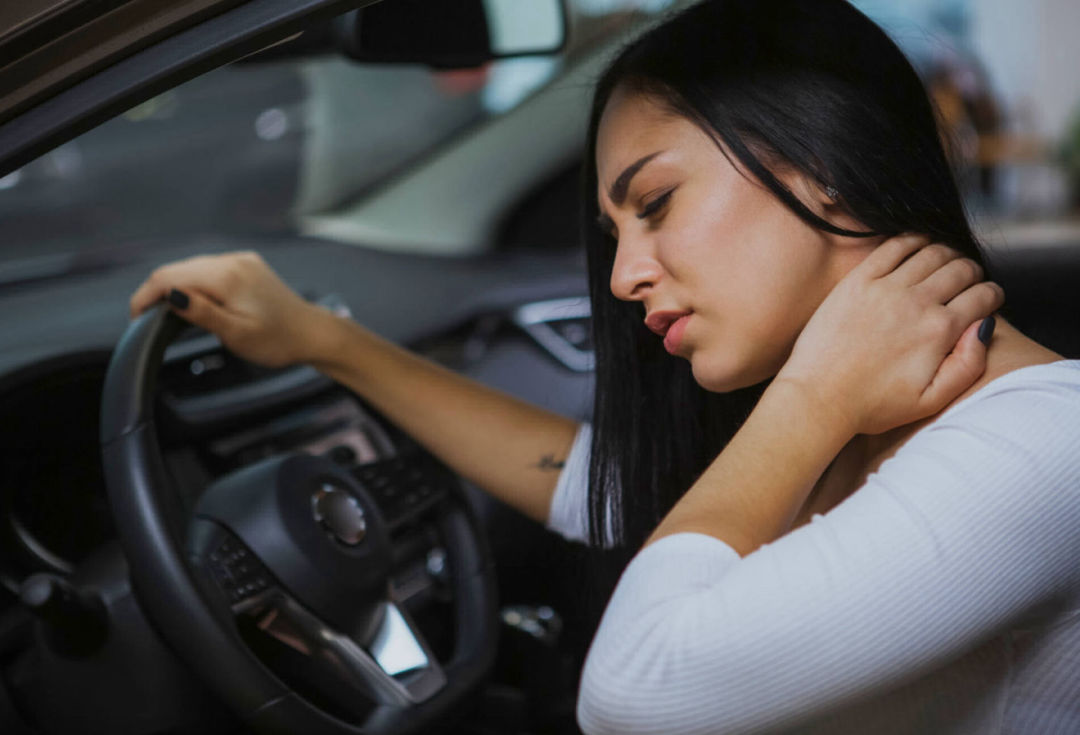 Una mujer con la mano en el cuello después de un accidente de auto