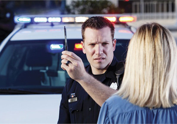 Un policia haciendo una prueba de alcoholemia a una conductora